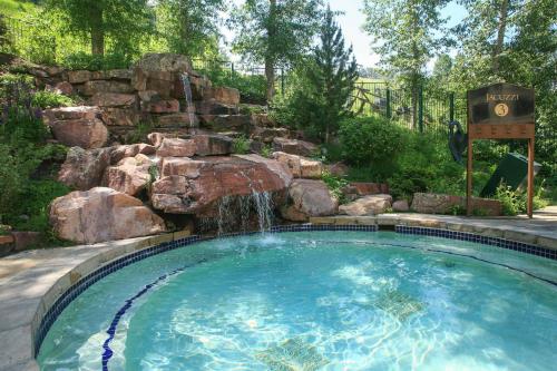 a swimming pool with a waterfall in a backyard at Village Hall 1415 by East West Hospitality in Beaver Creek