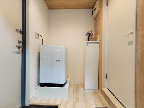 a small white refrigerator in a room with a door at D12新宿最中心 两室 新大久保站5分-2 rooms Shinjuku center 5 mins to ST Max 4P 新宿 涉谷 表参道 池袋 上野 代代木 银座 原宿 in Tokyo