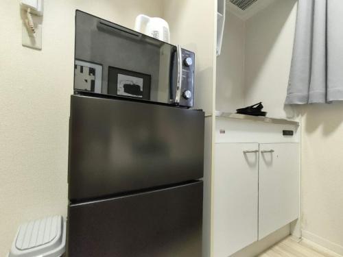 a black refrigerator with a microwave on top of it at D12新宿最中心 两室 新大久保站5分-2 rooms Shinjuku center 5 mins to ST Max 4P 新宿 涉谷 表参道 池袋 上野 代代木 银座 原宿 in Tokyo