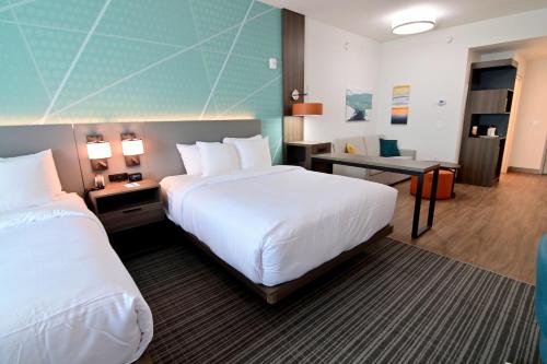 a hotel room with two beds and a desk at Comfort Suites Titusville near Kennedy Space Center in Titusville