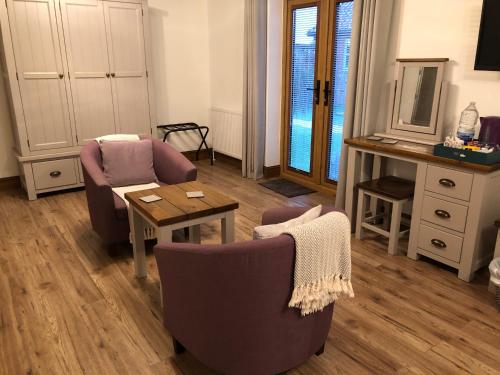 a living room with two chairs and a table at Grove Barn Bed and Breakfast in Harleston