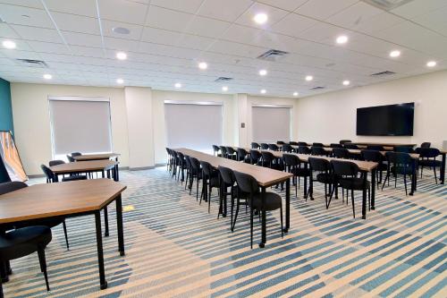 a conference room with tables and chairs and a screen at Comfort Suites Titusville near Kennedy Space Center in Titusville