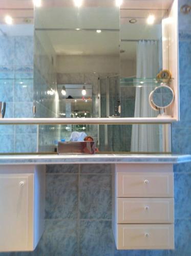 La salle de bains est pourvue d'un comptoir avec un miroir et un lavabo. dans l'établissement Nice port 4 pax, 2 chambres clim balnéo parking, à Nice