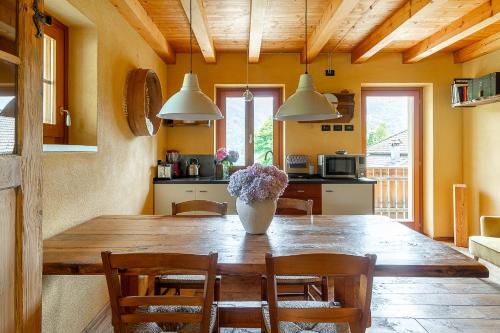 a dining room with a wooden table and a vase with flowers at Casa Anna in Trichiana