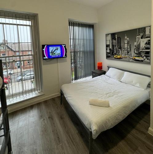 a bedroom with a bed and a tv on a wall at Westgate Apartments in Newcastle upon Tyne