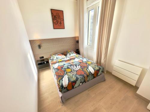 une chambre avec un lit avec une couette colorée et une fenêtre dans l'établissement Cosy Home Cannes - Croisette, à Cannes