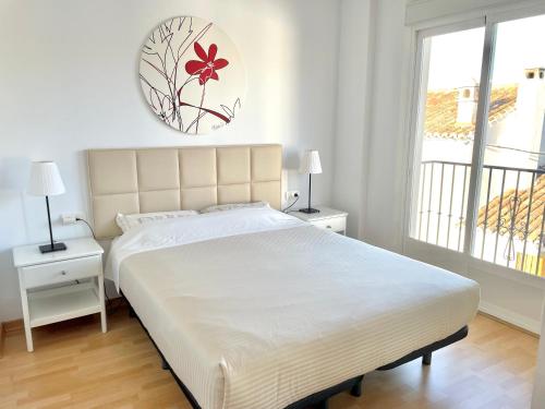 a white bedroom with a large bed and a window at Apartment with terrace in Ardales