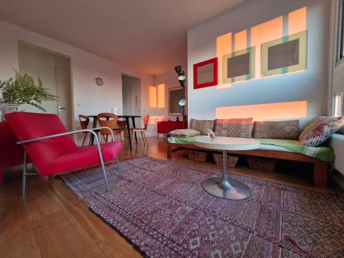 un salon avec une chaise rouge et un canapé dans l'établissement Loft 80m2 Parking Vues magiques, à Paris