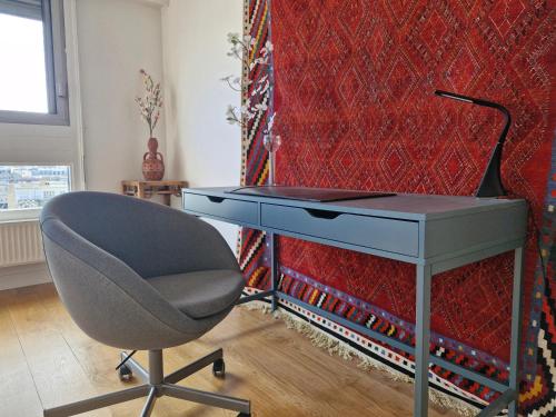 un bureau avec une chaise à côté d'un mur rouge dans l'établissement Loft 80m2 Parking Vues magiques, à Paris