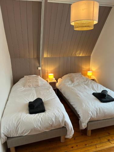 deux lits dans une chambre avec deux serviettes noires dessus dans l'établissement Ker Levenez - Maison en Pierre Perros-Guirec, à Perros-Guirec