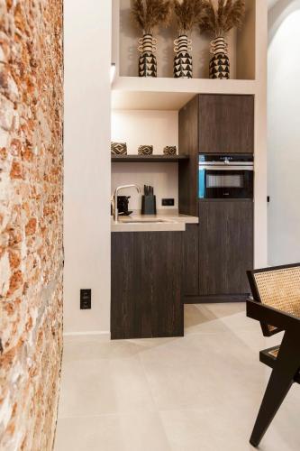 a kitchen with dark wood cabinets and a stone wall at BTFL Living Antwerp in Antwerp