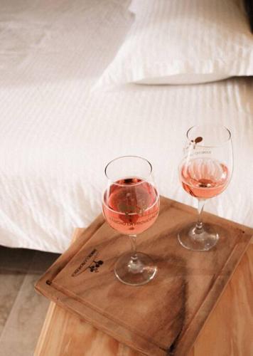 two glasses of wine on a wooden tray next to a bed at Hotel EL Porvenir in Tunas Blancas