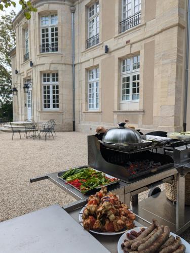 a grill with food on it in front of a building at Domaine de Coeurmandie - Hôtel Château in Bény-sur-Mer