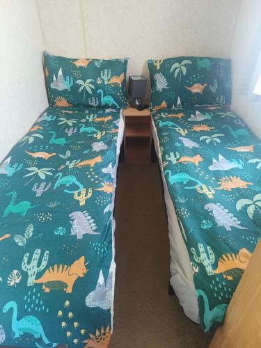 a bedroom with two beds with a green comforter at Mark and Teresa's 8 berth caravan on Coral Beach Ingoldmels in Ingoldmells