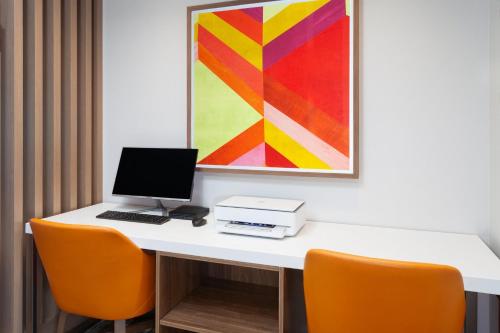 a desk with a laptop computer and orange chairs at Holiday Inn Express & Suites Reedsburg - Dells Area by IHG in Reedsburg