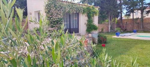 un jardín con una casa y una piscina en Gite LA DEPENDANCE, en Le Cailar