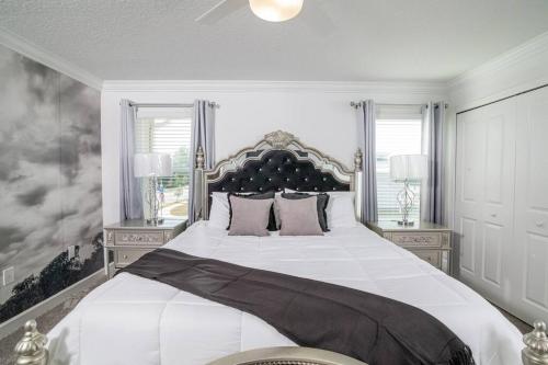 a bedroom with a large white bed with two windows at EPIC STYLISh retreat With Free water park near Disney in Kissimmee