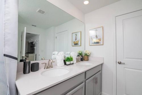 a white bathroom with two sinks and a mirror at EPIC STYLISh retreat With Free water park near Disney in Kissimmee