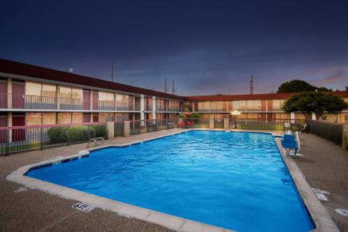 a large swimming pool in front of a building at Red Roof Inn & Conference Center McKinney in McKinney