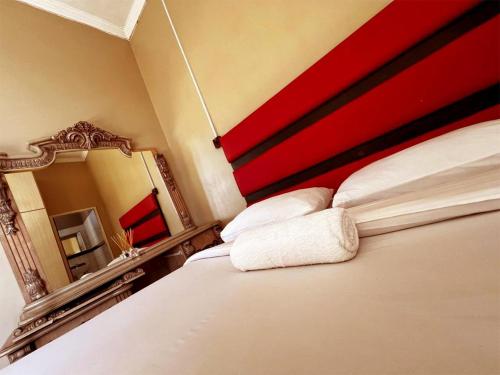 a bedroom with a bed with a red headboard and a mirror at Ebony Guest House in Pretoria