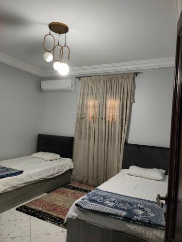 ein Schlafzimmer mit zwei Betten und einem Kronleuchter in der Unterkunft فيللا في التجمع الأول in Kairo