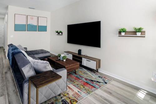 a living room with a couch and a flat screen tv at Beautiful Home, Walk to UF, Newly built in Gainesville