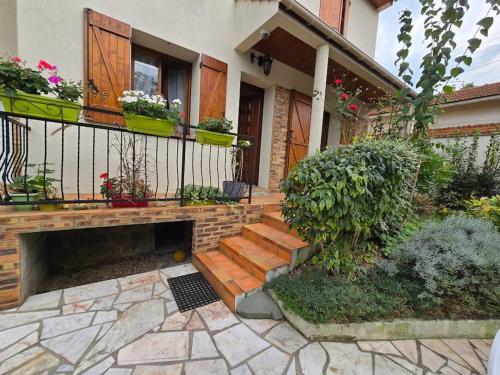 a house with a staircase and a balcony with plants at duplex en maison individuelle de 70 m2avec jardin in Viry-Châtillon