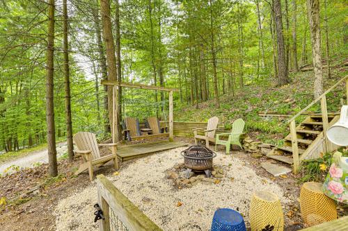 a backyard with chairs and a fire pit in the woods at Carrollton Cabin with Patio and Fire Pit! in Carrollton