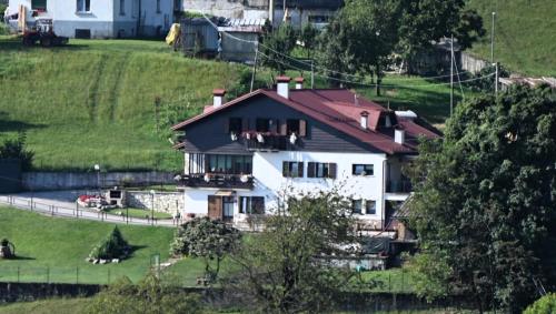 a white house with a red roof on a hill at La casa di Rosy in Enego