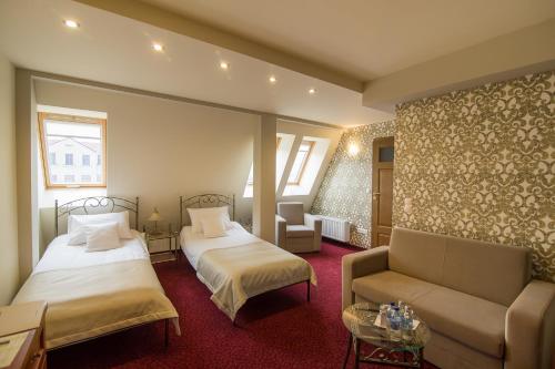 ラチブシュにあるZajazd Biskupiのベッド2台とソファが備わるホテルルームです。