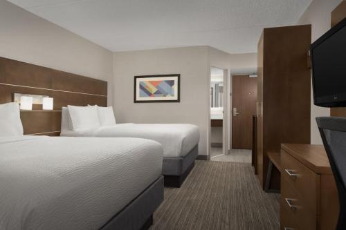 a hotel room with two beds and a flat screen tv at Holiday Inn Express Andover North - Lawrence by IHG in Lawrence