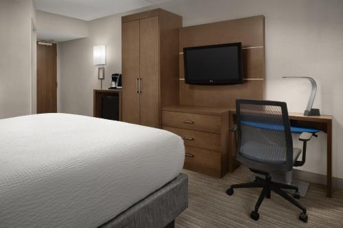 a hotel room with a bed and a chair and a television at Holiday Inn Express Andover North - Lawrence by IHG in Lawrence