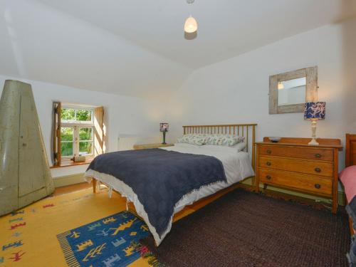 een slaapkamer met een bed, een ladekast en een raam bij Heather Cottage in Penzance