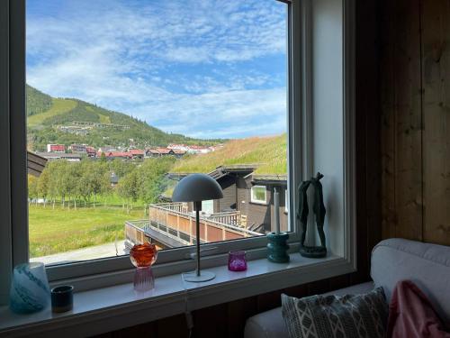 a window with a lamp and a view of a house at Sentral leilighet på Geilo in Geilo