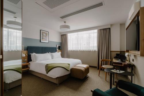 a hotel room with a large bed and a desk at Club Quarters Hotel London City, London in London