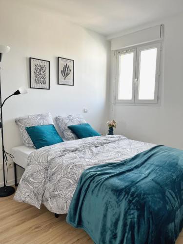 a bedroom with a large bed with blue pillows at COSY NOISY Charmant 2 pièces entre Paris et DisneyLand in Noisy-le-Grand
