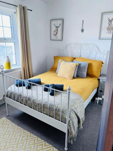 a bedroom with a bed with yellow sheets and blue pillows at Family & friends get together birthday hot tub in Porthcawl
