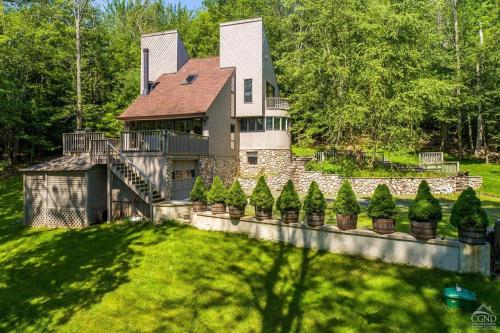 une grande maison avec un mur en pierre et des arbres dans l'établissement Alpine 5BR Chalet 6 min Away to SKI, à Windham