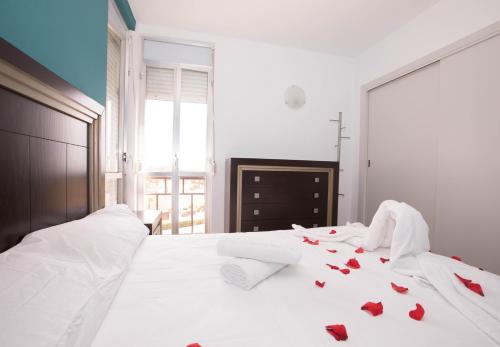 a bedroom with a white bed with red roses on it at Apartamento Babor Sun & Beach in Almerimar