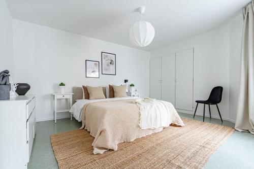 a white bedroom with a bed and a chair at Affordable 2BR in eclectic SoFo - construction work in Stockholm