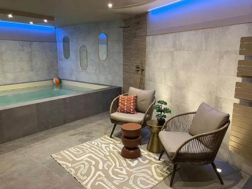 une salle de bains avec deux chaises et une piscine dans l'établissement Villa Kerleven- 150m plage - Spa intérieur-piscine, à La Forêt-Fouesnant