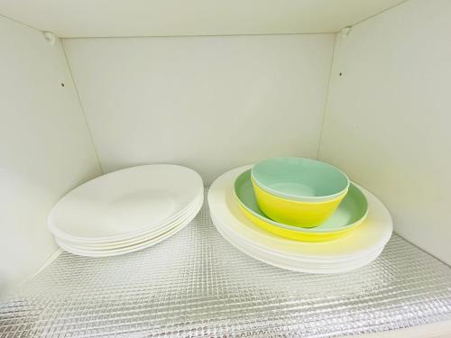 two plates and bowls sitting on plates in a cabinet at ELYSIA-Near Gleaneagles & Legoland-2RB WarmQ Suite Max7pax-WaterDispenser in Nusajaya