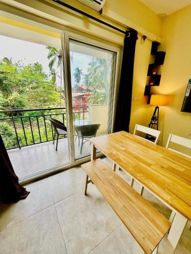 a dining room with a wooden table and a balcony at Sea breeze 1 bhk apartment A12 Calangute,North Goa in Nagoa-Bardez
