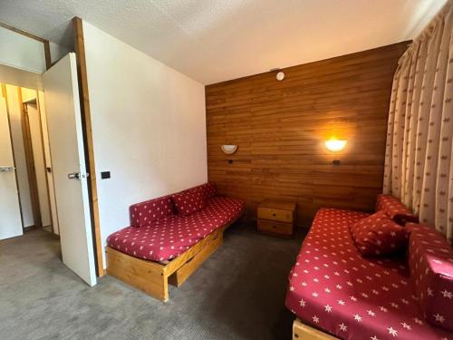 une chambre avec un canapé rouge et un banc rouge dans l'établissement Residence 3000 Bail - Studio pour 4 Personnes 31, à Mâcot La Plagne