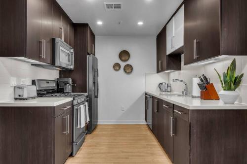 a kitchen with brown cabinets and white counter tops at Modern & chic in Heart of Downtown Santa Monica in Los Angeles