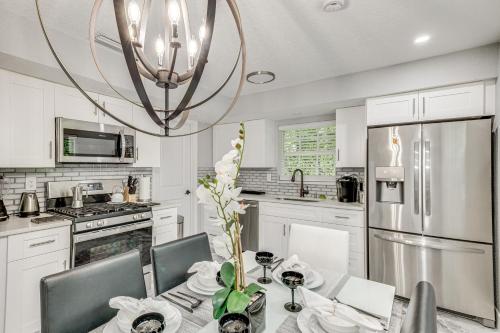 a white kitchen with a table and a chandelier at Pet-Friendly Gem with Pool and Yard in West Palm Beach in West Palm Beach
