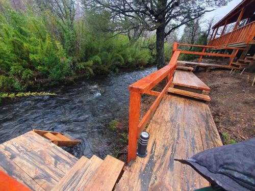 a wooden bridge over a river next to a house at Tiny & Big House Suite Los Mallines de Malalcahuello in Malalcahuello