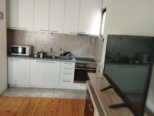 a kitchen with white cabinets and a sink and a microwave at Riki Apartments in Sarajevo