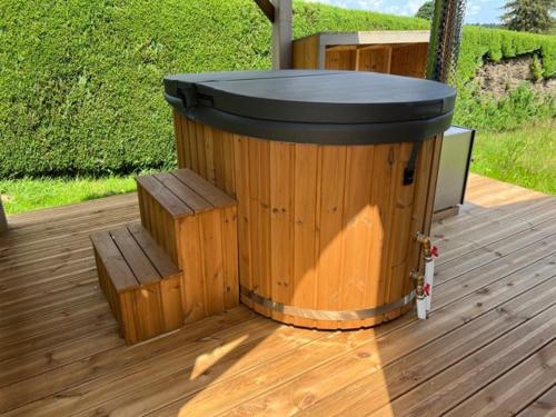 un tonneau en bois assis sur une terrasse avec deux bancs dans l'établissement La Tiny House, La Chandeleytte, à Champdray