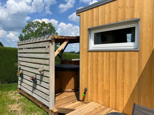 un hangar en bois avec une fenêtre et une poubelle dans l'établissement La Tiny House, La Chandeleytte, à Champdray